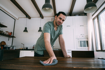 Fototapeta premium A young man is cleaning, dusting the table in the kitchen and living room at home.
