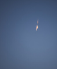 The plane flies on the blue sky and leaves a trail of burnt gases in the atmosphere, minimalism for the background