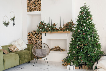 Rustic home interior of the living room with a Christmas wreath, fireplace, firewood, sofa and Christmas tree. Decorations for the celebration of Christmas holidays - obrazy, fototapety, plakaty