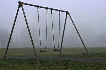 A empty swingset on a foggy autumn morning.