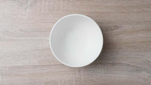 empty bowl on wood table top. Close up hand sliding empty dish on wood table.