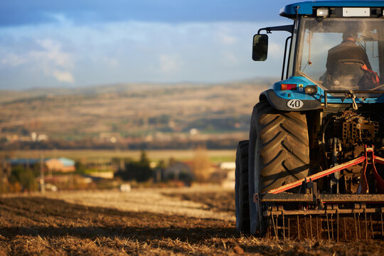 Fototapeta Tractor with plow working soil of agricultural field