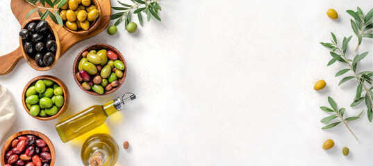 Fototapeta na wymiar Different olives in bowls on white concrete background. Top view of olives, olive leaves and bottle of olive oil. Diet food concept. Banner.
