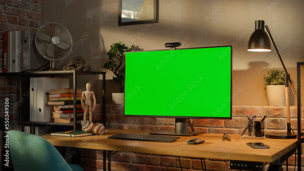 Aufkleber Modern Personal Computer Monitor with Green Screen Mock Up Display Standing on the Desk with Keyboard, Mouse, Pens, Notebooks and Headphones. Cozy Home Office in Loft Living Room Space.