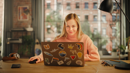 Beautiful Young Woman Working on Laptop Computer while Sitting in Stylish Cozy Creative Office....
