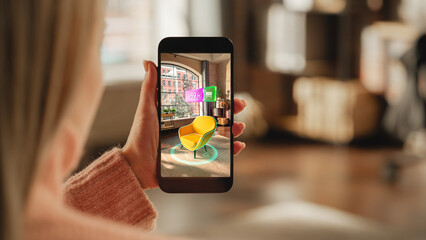 Over the Shoulder Footage of a Female Hand, Holding Smartphone with an Augmented Reality Display Showing a Chair. Woman Doing Online Shopping and Checking her Options In Live Situation In Distance