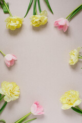 Beautiful composition frame of spring flowers. Bouquet of pink and yellow tulips on a pastel beige background. Valentine's Day, Easter, Birthday, Happy Women's Day, Mother's Day. Flat lay, top view