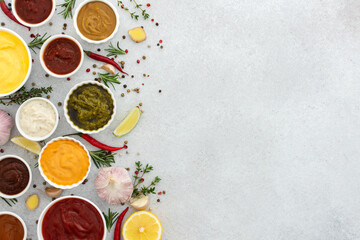 Different types of sauces in bowls with seasonings, rosemary and pepper, thyme and garlic, lime and lemon, cilantro, top view, copy space