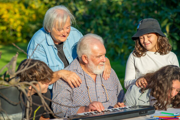Grandfather playing outdoor with his grandchildren with music instruments.