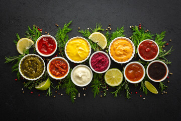 Different types of sauces in bowls with seasonings, rosemary and dill, thyme and and peppercorns, top view, copy space