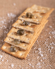 Some wholegrain crackers are stacked like a stairway, with capers and rock salt on and around