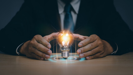 Businessman hand showing power with light bulb on table, concept creativity, innovation , learning, inspiration , science and communication technology to develop the business of the organization