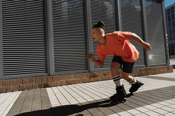 Positive man roller skating on urban street at daytime.