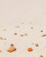 Natural stones amber yellow colored on beige sand. Aesthetic minimal nature scene with pebble stones on fine sandy background. Summer vacation or relaxation concept, selective focus