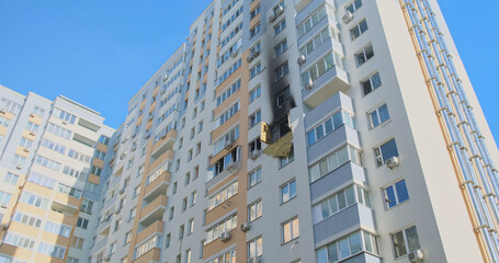 Corner tall residential building. Black window, apartment after the fire. Low angle, panorama.