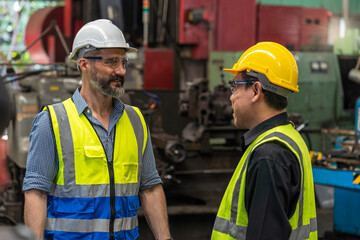 Engineer discuss with Technician in factory. Man technician is working in a steel factory. Man worker in safety helmet working on steel machine.