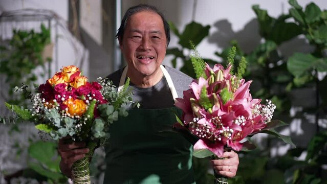 Happy small business entrepreneur holding bouquet of flower roses arrangement ready for customer. An Asian florist showing decorative gift