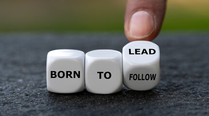 Hand turns dice and changes the expression 'born to follow' to 'born to lead'.
