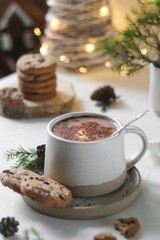 A cup of cocoa with cookies stands on a white table, christmas background, bokeh