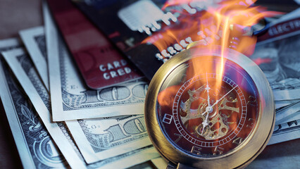 Burning pocket watch, credit cards and dollars in cash