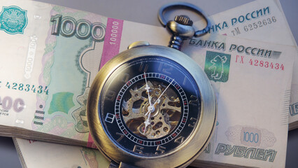Pocket watch with pile of money in wrapper