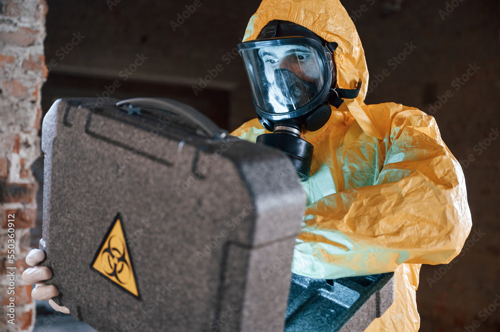 Wall mural Frightened scientist is with radioactive materials. Man dressed in chemical protection suit in the ruins of the post apocalyptic building - Wall murals