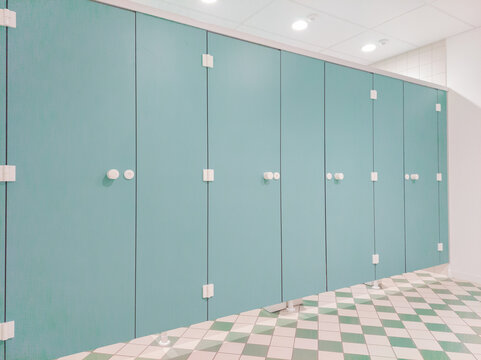 Lightblue toilet cubicles in a row, sanitairy block with nice diamond-shaped floor pattern. Image taken indoor in Leuven, Belgium.