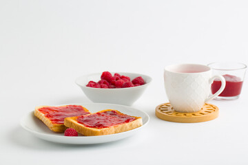 Cup of red tea and toasted bread with raspberry jam