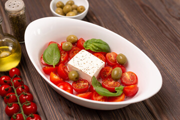 Cherry tomatoes with salted cheese, basil and olives in a deep dish prepared for baking