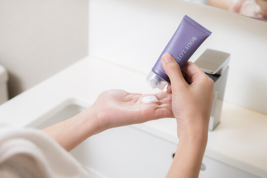 Close up of women applying body lotion cream on hand.