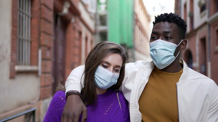 Interracial couple wearing covid-19 face mask walking outside