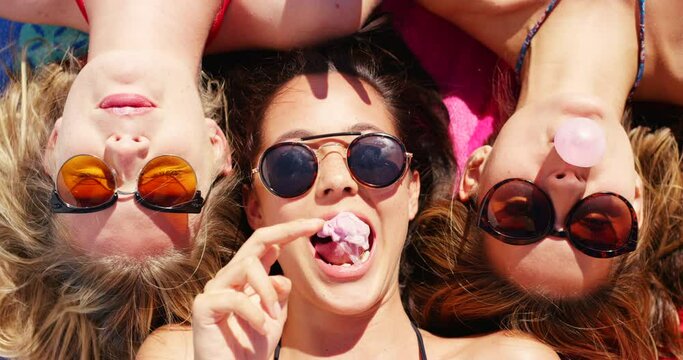 Top view of women, friends and blowing bubblegum outdoors on holiday, having fun and bonding. Peace sign, chewing gum and group of girls with sunglasses relaxing, laughing and enjoying time together.