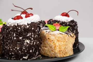 Cakes with chocolate, cherries and cream on a white background.