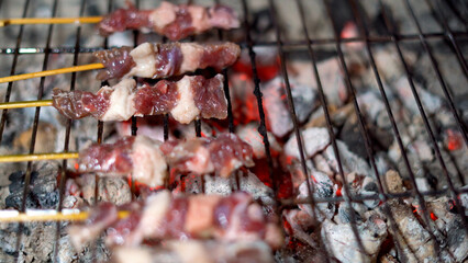 Close up street food seller is grilling barbecue beef on skewers.