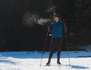 Portrait handsome male athlete with cross country skis, taking fresh breath and having break after...