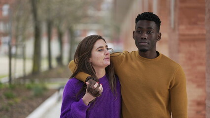 Interracial couple relationship. black man arms around girlfriends walking together outside