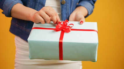 Closeup of a female hands opening a gift box, woman with gifts isolated over color background, Diwali, Christmas, New Year, Festival, Birthday concept
