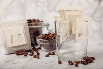 Trends in making coffee at home. Drip bag of fresh drink in a glass with coffee beans on a brown...