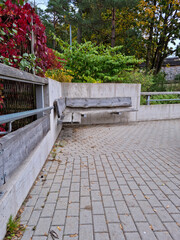 Obraz premium Bench at the public park. Modern recreation place. Pathway in perspective. Concrete and timber in modern architecture.