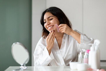 Happy arab woman using natural massager, enjoying healthy glowing skin