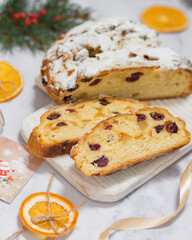 Christmas stollen with candied fruits and dried fruits on a wooden board, next to a spruce branch with a festive atmosphere. Traditional German dessert for Christmas celebration.