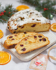 Christmas stollen with candied fruits and dried fruits on a wooden board, next to a spruce branch with a festive atmosphere. Traditional German dessert for Christmas celebration.