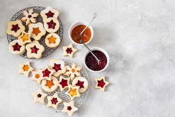Obraz na płótnie Canvas Traditional Linzer Christmas cookies filled with lingonberry jam and orange jam on wooden background