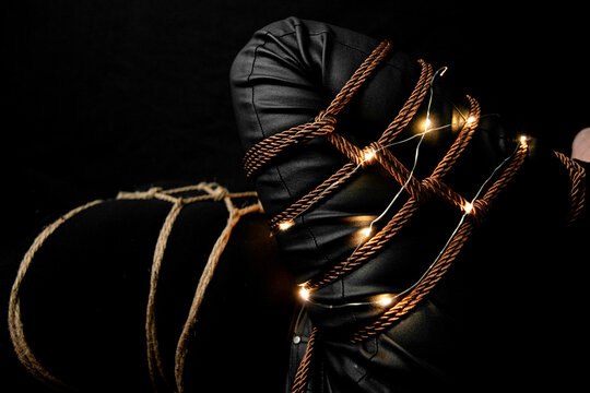 Woman with a Leg tied on a futomomo knot and a karada knot on her chest over a black velvet with lights and candle