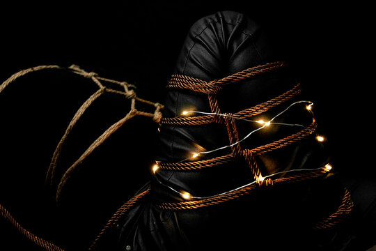 Woman with a Leg tied on a futomomo knot and a karada knot on her chest over a black velvet with lights and candle