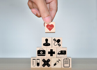 Health Insurance Concept, Hand of man holding wood cube stacking with icon healthcare medical on blue background, copy space.