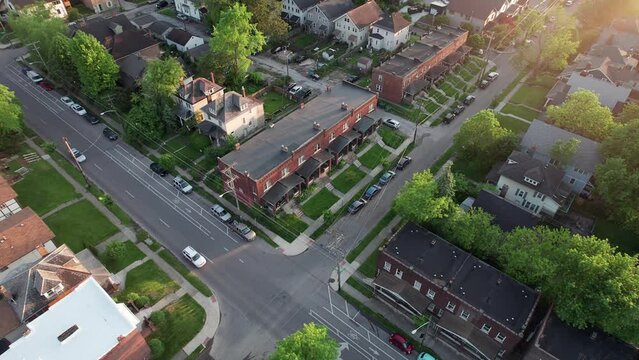 Wide high angle from aerial drone view of lower class urban neighborhood suburb with town houses, student housing, rental property, apartments, city streets, car traffic, and old, low income buildings
