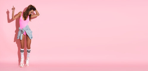 Perfect woman with roller skates on pink background.