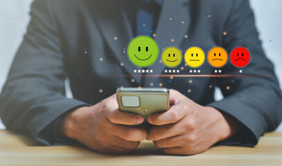 Customer service and Satisfaction concept,Businessman pressing smiley face emoticon on virtual touch screen,happy Smiley face icon to give satisfaction in service. rating very impressed