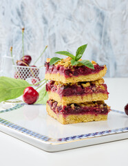 Square slices of cherry crumble lie in a stack on a white board